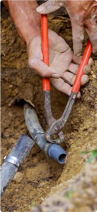 Technician repairing a buried irrigation pipe with pliers